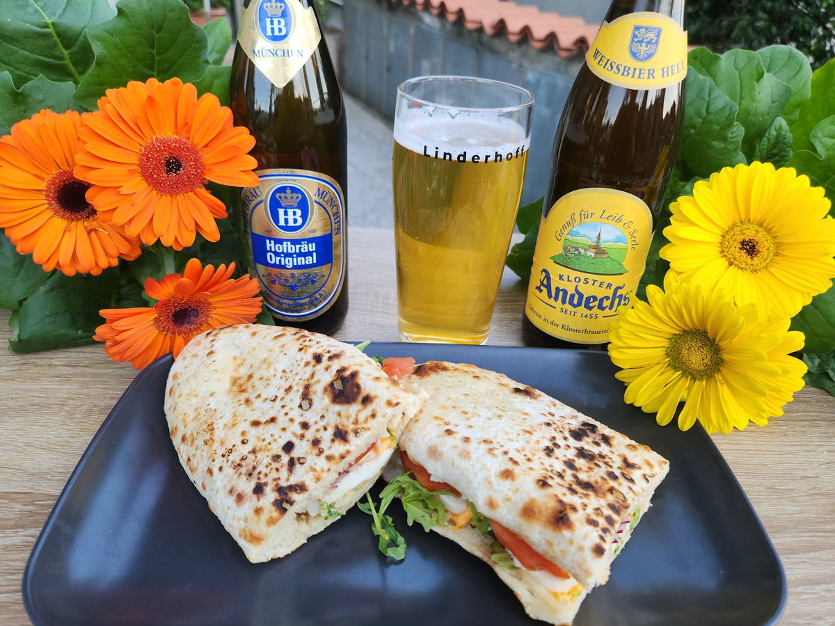 Birre in bottiglia e alla spina con un pane farcito, sul tavolo del dehors