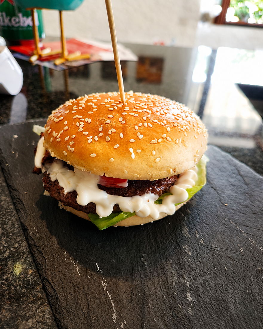 Hamburger di manzo con insalata e salsa, servito su ardesia