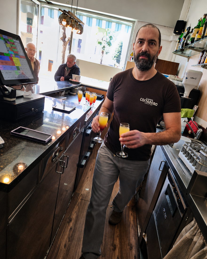 Leonardo dietro il banco del bar con due calici di aperitivo