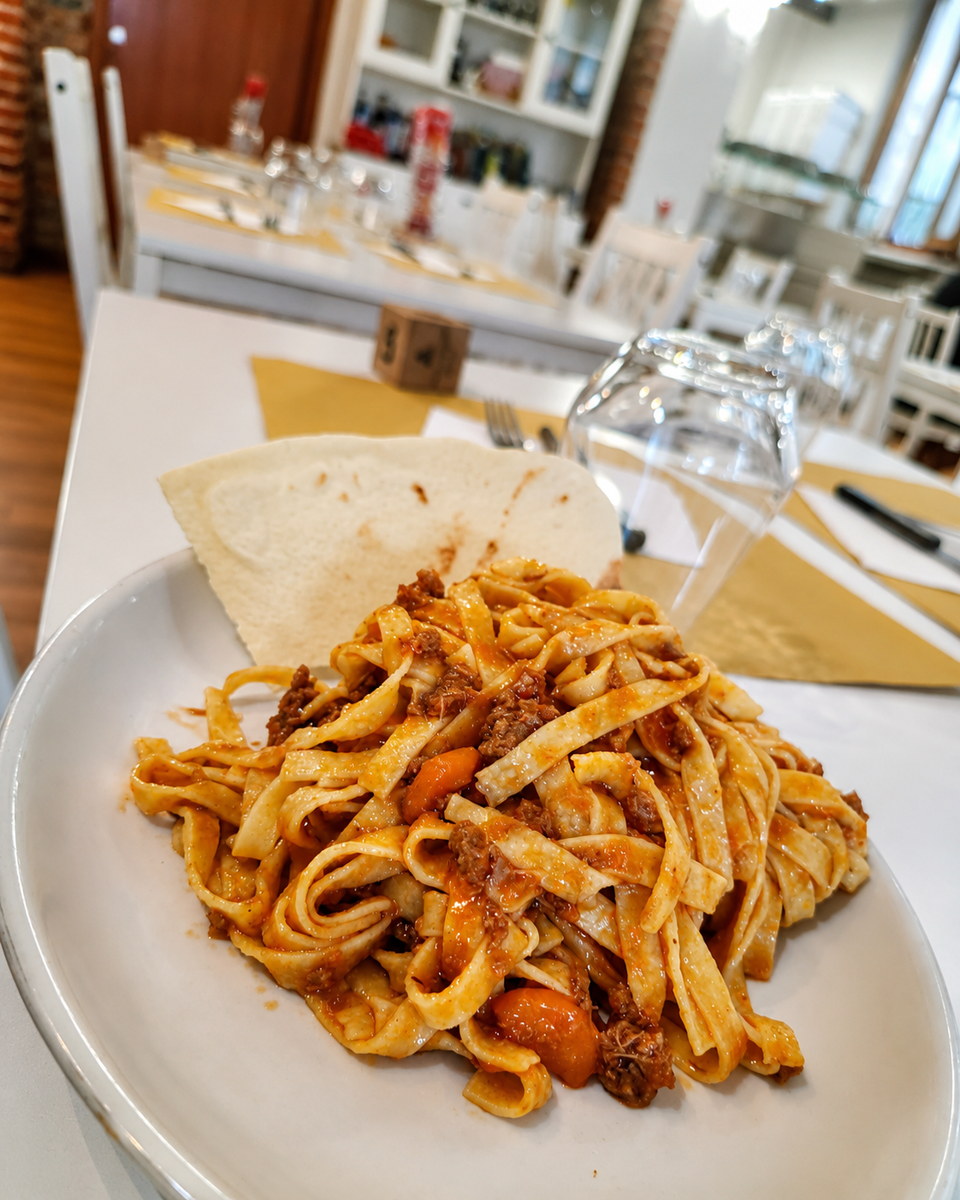 Tagliatelle fresche al ragù servite in sala, davanti all'arco in mattoni